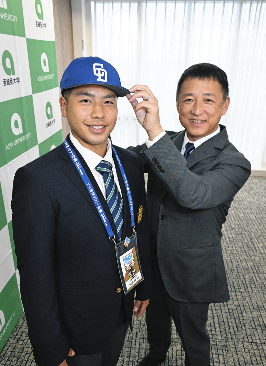 中日の正津スカウト（右）からドラフト３位指名のあいさつを受け、笑顔を見せる亜大・前嶋