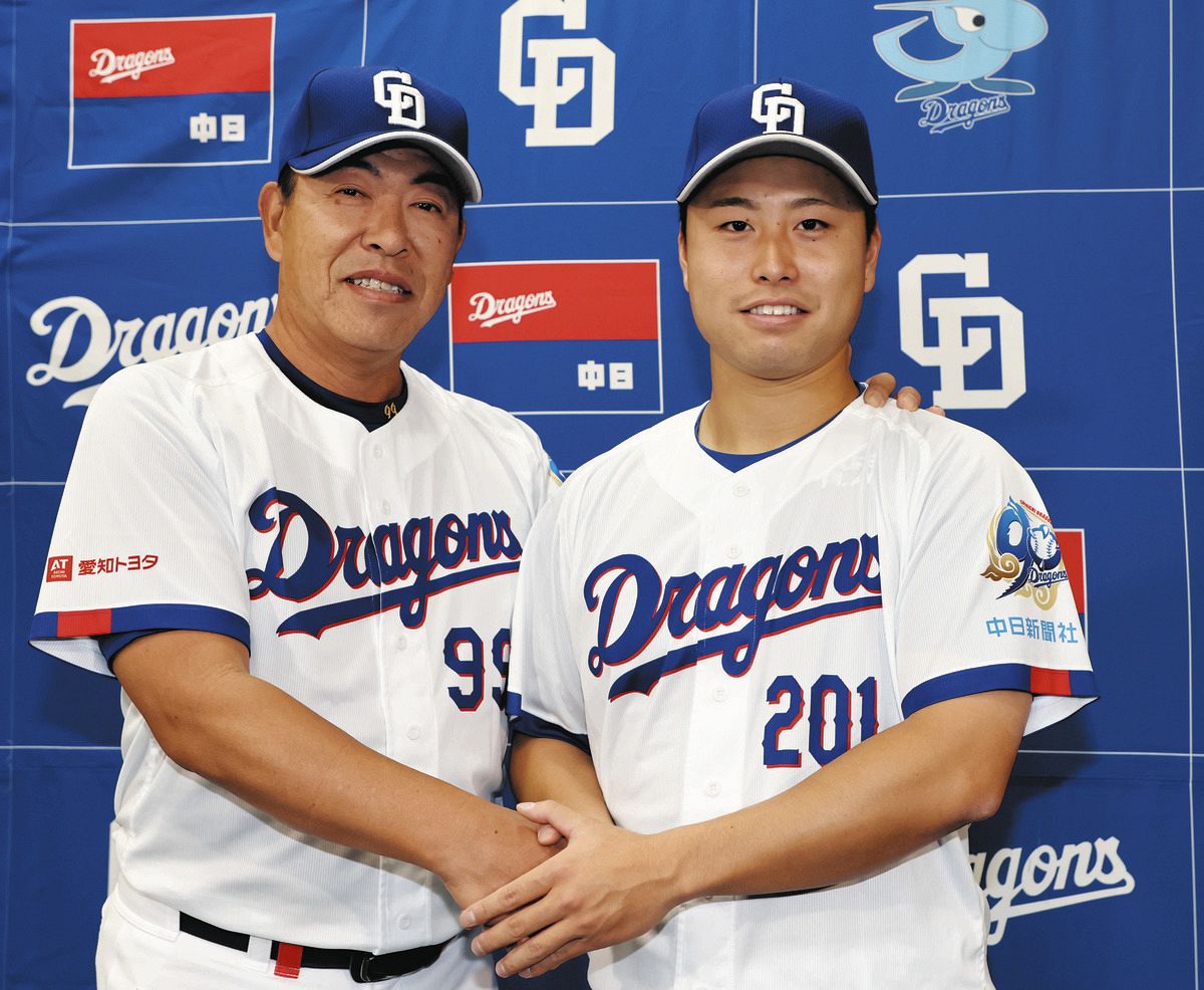 支配下登録され、井上監督（左）と握手する牧野