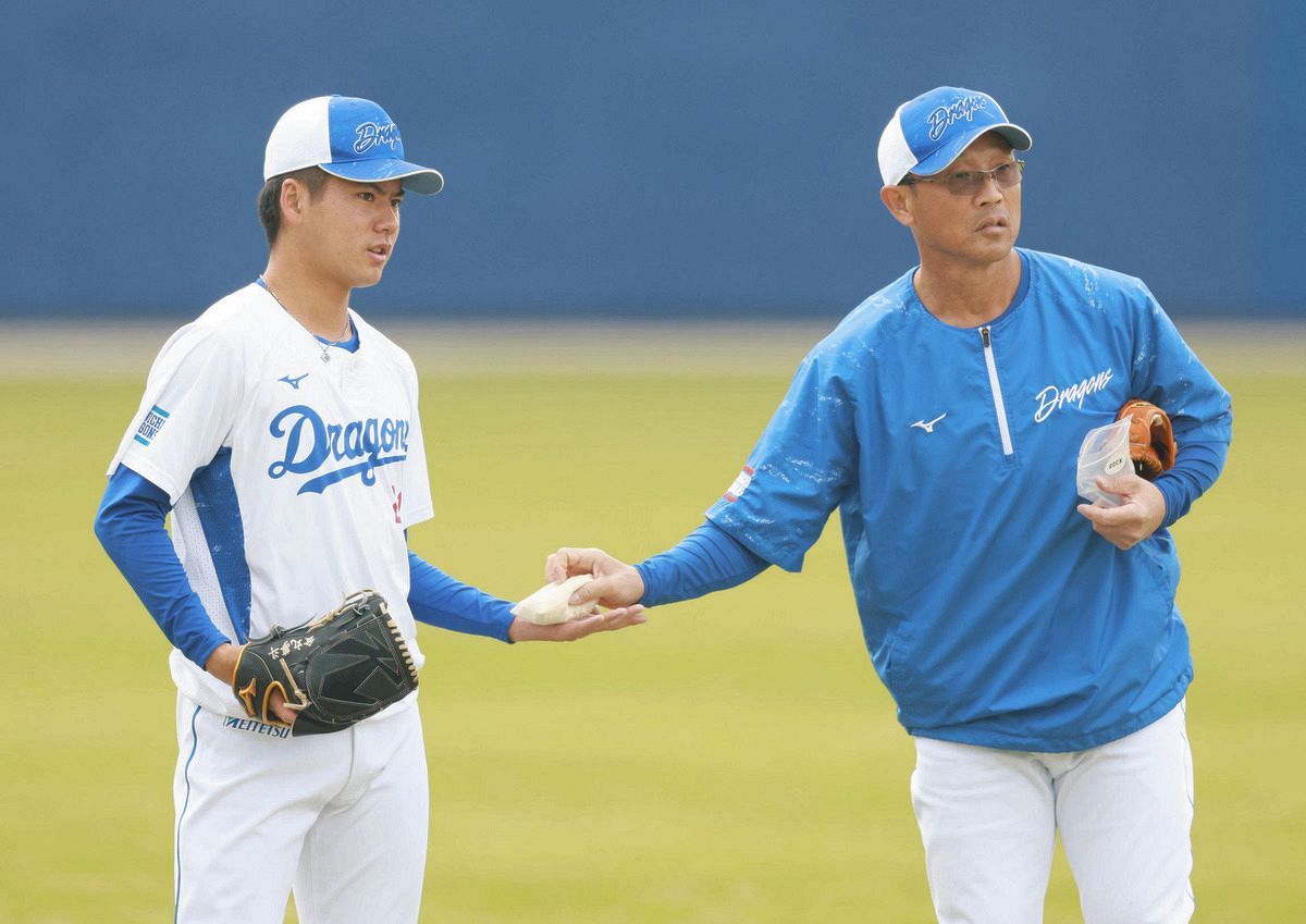 大塚巡回投手・育成コーチ（右）からＭＬＢ用のロジンを渡される金丸