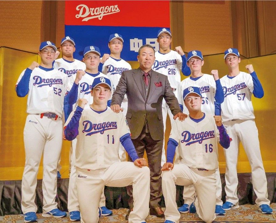 新入団発表会見で井上監督（中央）を囲みポーズをとる（前列左から）中西聖輝投手、桜井頼之介投手、（中列左から）篠崎国忠投手、能戸輝夢外野手、新保茉良内野手、花田旭外野手、
（後列左から）三上愛介外野手、牧野憲伸投手、石川大峨内野手＝２０２５年１２月１０日、名古屋市内のホテルで