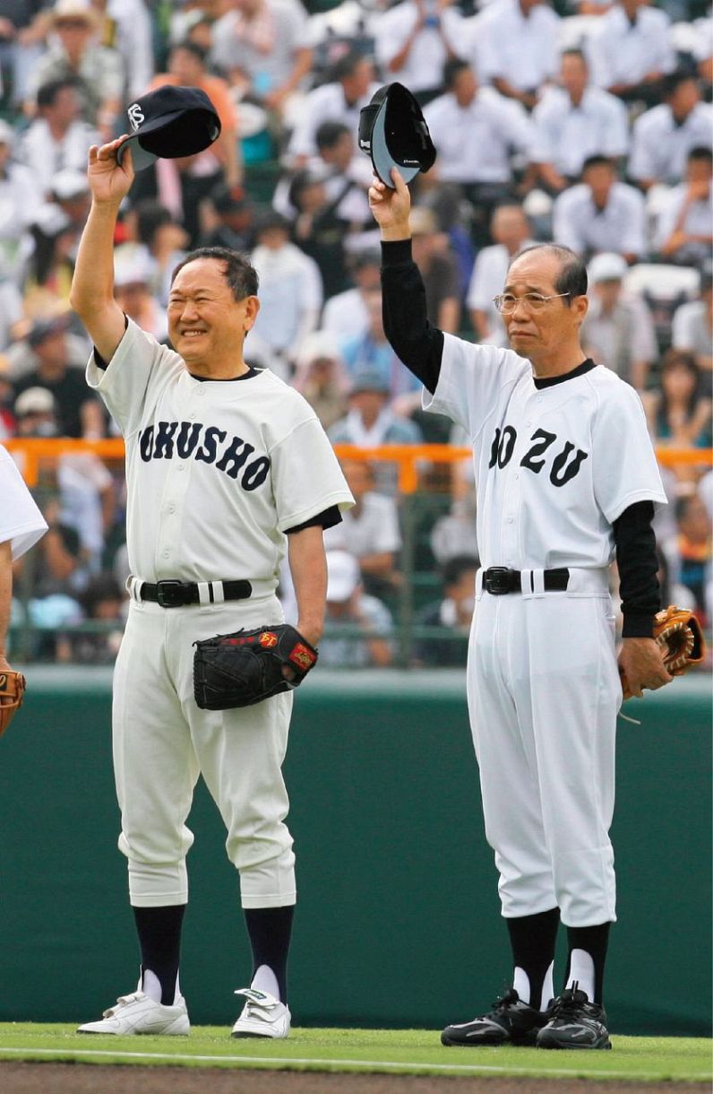 ２００８年夏の甲子園大会開会式セレモニーで観客に帽子を振る徳島商ＯＢの板東英二さん㊧と魚津ＯＢの村椿輝雄さん。両校は１９５８年夏の大会準々決勝で27㌄を戦った（立浪基博撮影）