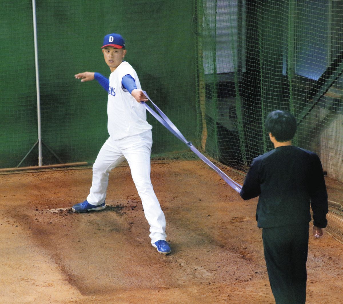 ブルペンの傾斜でチューブを使ったメニューに取り組む松山