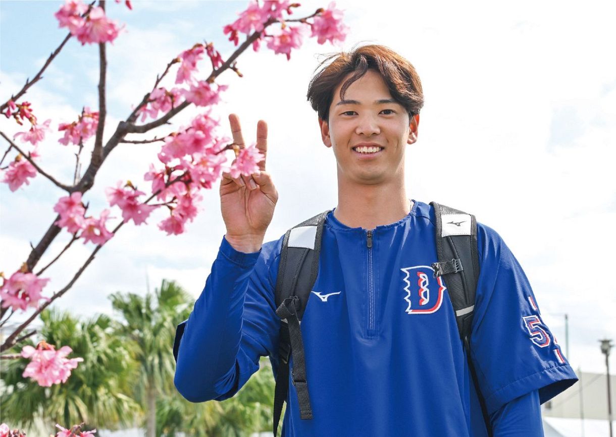 カンヒザクラと写真に納まる花田＝２月１８日、沖縄・北谷で