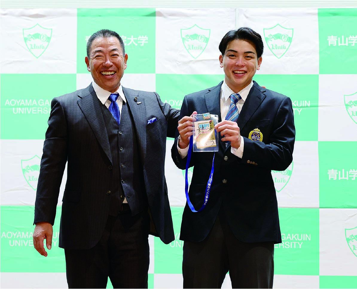 ドラフト会場から駆けつけた井上監督にIDパスを渡され、笑顔の青学大・中西=10月23日、東京都渋谷区で